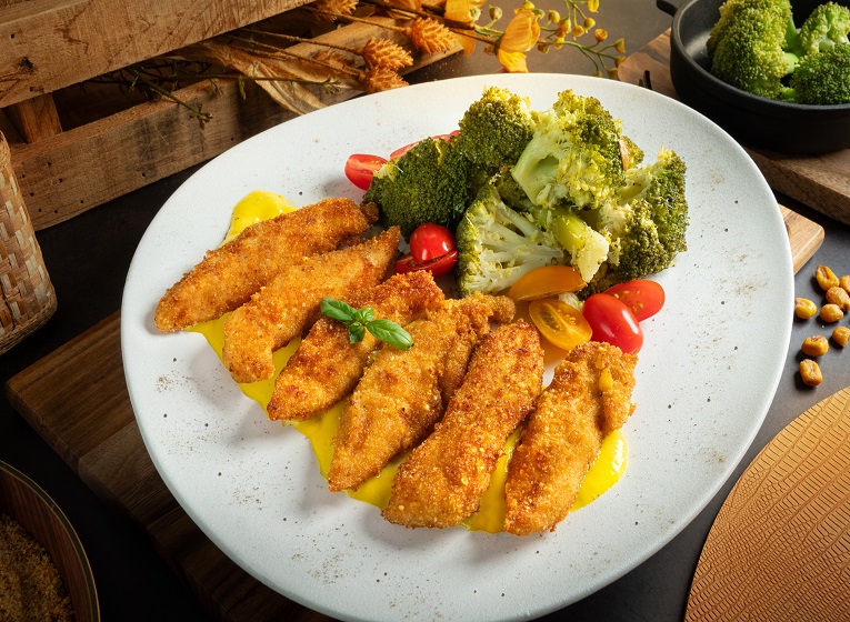 Plato de solomillos de pollo crujientes al maíz con salsa de mango.