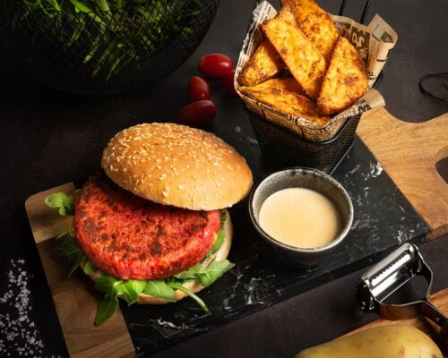 Plato con hamburguesa de pollo y remolacha casera con salsa de queso San Simón da Costa y patatas Deluxe.