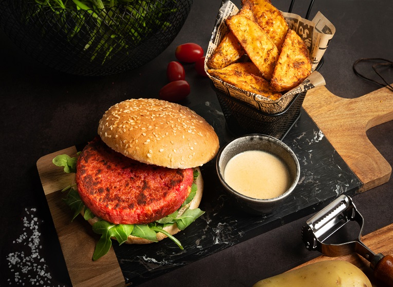 Plato con hamburguesa de pollo y remolacha casera con salsa de queso San Simón da Costa y patatas Deluxe.