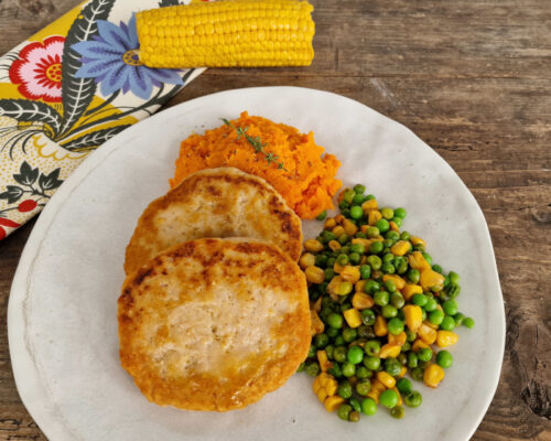 Plato con hamburguesas de pollo de corral con boniato, guisantes y maíz.