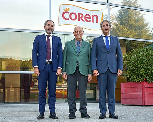 Tres directivos de Coren posando ante la sede de la cooperativa bajo el logotipo de Coren, con Manuel Gómez-Franqueira en el centro